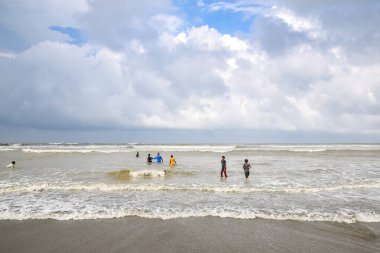 Denizin ortasında yürüyen bir sürü insanın olduğu güzel bir sahil manzarası. Cox 's Bazar plajı dünyanın en uzun plajıdır. Bangladeş 'te çok popüler bir tatil beldesi..