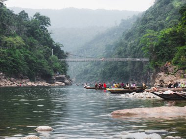 Bir grup insan nehirde tekneye biniyor.