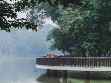 Ramna parkında, göl kıyısında yürüyen insanlar..