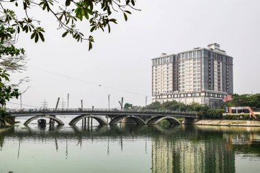 Şehirdeki bir göldeki yüksek katlı bir binanın manzarası.