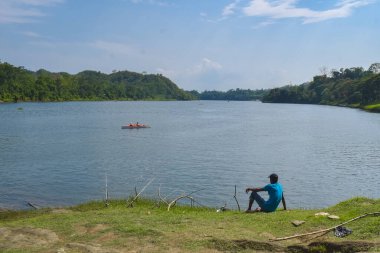 Güzel yeşil bir gölde bir teknede oturan balıkçı..