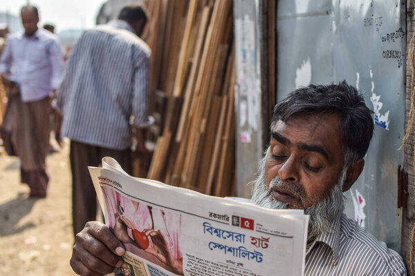 мужчина читает ежедневную газету на улице.