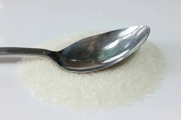 Beyaz arkaplanda izole edilmiş çay kaşığı şeker