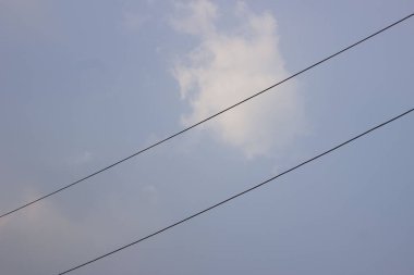 Dalgalı bulutlarla bezenmiş uçsuz bucaksız mavi gökyüzünün manzarası bir merak ve sükunet hissi uyandıran bir tablo yaratıyor..