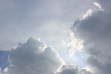 Mavi gökyüzü ve güneş bulutlarla kaplı. Yumuşak, dağınık bir parıltı yaratıyor. Bu parıltı manzarayı ılık ışıkla yıkıyor.. 