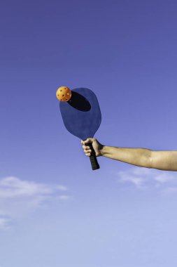 Kolu mavi raketle turuncu topa vuruyor.