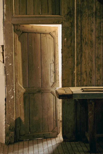 Old open wooden door through which the light enters and goes to the lower area of the workshop