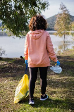 Güneşli bir günde sırtüstü yatıp gönüllü olarak çöp toplayan bir kadın.