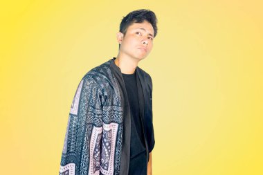 Üzerinde desenli detaylar olan siyah bir kıyafet giyen bir adam, parlak sarı bir arka plan karşısında hayal kırıklığına uğramış veya hayal kırıklığına uğramış bir ifadeyle telefonunu kulağına tutar. Kötü haberlerle ilgili konular, zor konuşmalar, alışkanlık