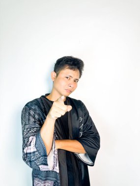 Siyah kimono tarzı bornoz giyen genç bir adam kararlı bir ifadeyle parmağını ileri doğru doğrultuyor. İddialı vücut dili liderlik, motivasyon ve cesaret veriyor. Bu resim otoriteyle ilgili kavramlar için mükemmeldir., 