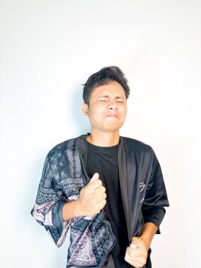 Siyah kimono tarzı bornoz giyen genç bir adam yumruklarını gergin bir yüz ifadesiyle sıkar, gözleri kapalı ve dudakları birbirine yapışır. Vücut dili hayal kırıklığı, öfke ya da duygusal sıkıntı olduğunu gösteriyor. Bu resim rela temaları için idealdir