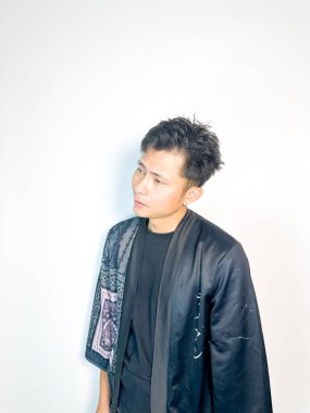 Geleneksel desenli siyah bornoz giyen genç bir adam, kafası karışık bir ifadeyle yana bakıyor. Onun hafif eğimli kafası ve çatık kaşları şüphe, merak ya da belirsizlik taşır, bu görüntü kafa karışıklığı, karar-mak temaları için uygundur