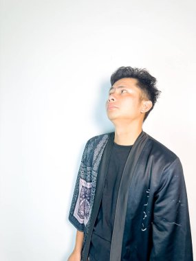 Geleneksel desenli siyah bornoz giyen genç bir adam, kafası karışık bir ifadeyle yana bakıyor. Onun hafif eğimli kafası ve çatık kaşları şüphe, merak ya da belirsizlik taşır, bu görüntü kafa karışıklığı, karar-mak temaları için uygundur