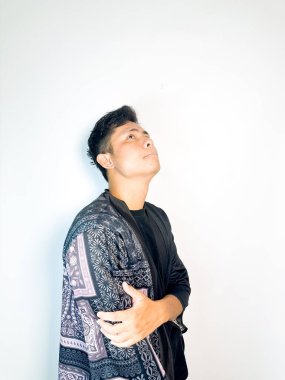 Geleneksel desenli siyah bornoz giyen genç bir adam, kafası karışık bir ifadeyle yana bakıyor. Onun hafif eğimli kafası ve çatık kaşları şüphe, merak ya da belirsizlik taşır, bu görüntü kafa karışıklığı, karar-mak temaları için uygundur