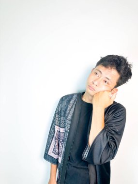 Geleneksel desenli siyah bornoz giyen genç bir adam, kafası karışık bir ifadeyle yana bakıyor. Onun hafif eğimli kafası ve çatık kaşları şüphe, merak ya da belirsizlik taşır, bu görüntü kafa karışıklığı, karar-mak temaları için uygundur