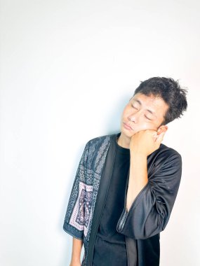 Geleneksel desenli siyah bornoz giyen genç bir adam, kafası karışık bir ifadeyle yana bakıyor. Onun hafif eğimli kafası ve çatık kaşları şüphe, merak ya da belirsizlik taşır, bu görüntü kafa karışıklığı, karar-mak temaları için uygundur