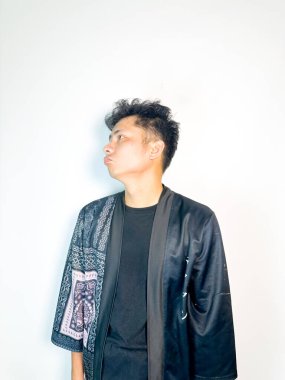 Geleneksel desenli siyah bornoz giyen genç bir adam, kafası karışık bir ifadeyle yana bakıyor. Onun hafif eğimli kafası ve çatık kaşları şüphe, merak ya da belirsizlik taşır, bu görüntü kafa karışıklığı, karar-mak temaları için uygundur