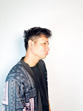 Geleneksel desenli siyah bornoz giyen genç bir adam, kafası karışık bir ifadeyle yana bakıyor. Onun hafif eğimli kafası ve çatık kaşları şüphe, merak ya da belirsizlik taşır, bu görüntü kafa karışıklığı, karar-mak temaları için uygundur