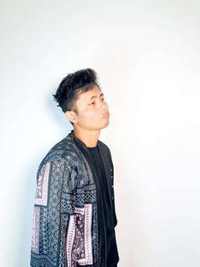 Geleneksel desenli siyah bornoz giyen genç bir adam, kafası karışık bir ifadeyle yana bakıyor. Onun hafif eğimli kafası ve çatık kaşları şüphe, merak ya da belirsizlik taşır, bu görüntü kafa karışıklığı, karar-mak temaları için uygundur