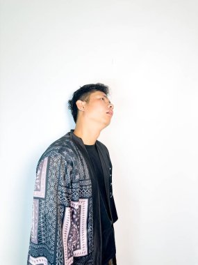 Geleneksel desenli siyah bornoz giyen genç bir adam, kafası karışık bir ifadeyle yana bakıyor. Onun hafif eğimli kafası ve çatık kaşları şüphe, merak ya da belirsizlik taşır, bu görüntü kafa karışıklığı, karar-mak temaları için uygundur