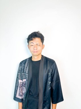 Siyah kimono tarzı bornoz giyen genç bir adam neşeli ama tarafsız bir ifadeyle göz kırpıyor. Onun rahat duruşu ve ince sırıtışı neşeli ve sıradan bir ruh hali yaratıyor. Bu görüntü mizah, güven, cazibe ve gelişigüzel intervatik kavramları için idealdir.