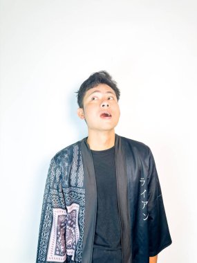 Siyah kimono tarzı bornoz giyen genç bir adam umut dolu ve düşünceli bir ifadeyle elini göğsüne koyar. Vücut dili minnettarlık, rahatlama ya da derin tefekkür iletir. Bu resim fait ile ilgili temalar için mükemmeldir