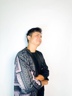 Geleneksel desenli siyah cüppeli genç bir adam başını hafifçe eğerken neşeli bir sırıtış yapar. Yüzündeki ifade eğlence, yaramazlık ya da hafif bir tepki veriyor. Bu da onu mizah, merak ya da iğneleme gibi kavramlar için ideal kılıyor..