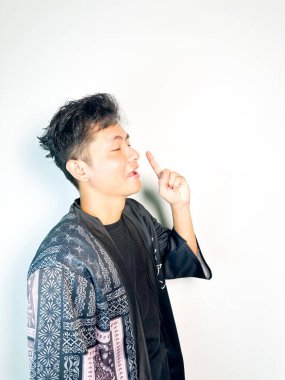 Geleneksel siyah bornoz giyen genç bir adam düşünceli görünürken işaret parmağıyla hareket ediyor. Bu ifade bir fikri veya farkındalığı akla getiriyor, beyin fırtınası, ilham ve problem çözme gibi kavramlara uygun kılıyor..