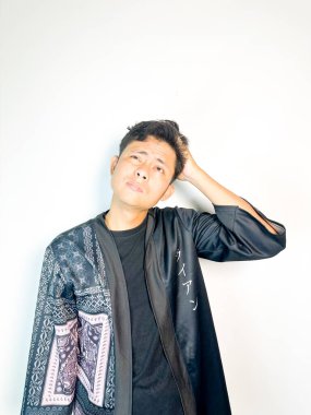 Geleneksel siyah bornoz giyen genç bir adam düşünceli görünürken işaret parmağıyla hareket ediyor. Bu ifade bir fikri veya farkındalığı akla getiriyor, beyin fırtınası, ilham ve problem çözme gibi kavramlara uygun kılıyor..