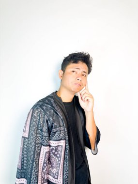 Geleneksel siyah bornoz giyen genç bir adam düşünceli görünürken işaret parmağıyla hareket ediyor. Bu ifade bir fikri veya farkındalığı akla getiriyor, beyin fırtınası, ilham ve problem çözme gibi kavramlara uygun kılıyor..