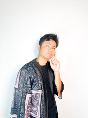 Geleneksel siyah bornoz giyen genç bir adam düşünceli görünürken işaret parmağıyla hareket ediyor. Bu ifade bir fikri veya farkındalığı akla getiriyor, beyin fırtınası, ilham ve problem çözme gibi kavramlara uygun kılıyor..