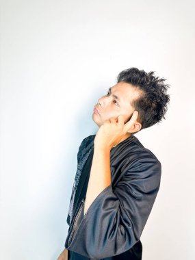 Geleneksel siyah bornoz giyen genç bir adam düşünceli görünürken işaret parmağıyla hareket ediyor. Bu ifade bir fikri veya farkındalığı akla getiriyor, beyin fırtınası, ilham ve problem çözme gibi kavramlara uygun kılıyor..