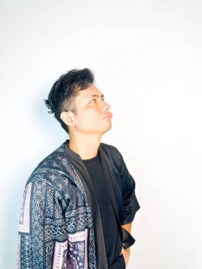 Geleneksel siyah bornoz giyen genç bir adam düşünceli görünürken işaret parmağıyla hareket ediyor. Bu ifade bir fikri veya farkındalığı akla getiriyor, beyin fırtınası, ilham ve problem çözme gibi kavramlara uygun kılıyor..