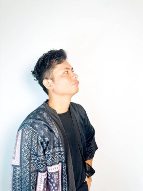 Geleneksel siyah bornoz giyen genç bir adam düşünceli görünürken işaret parmağıyla hareket ediyor. Bu ifade bir fikri veya farkındalığı akla getiriyor, beyin fırtınası, ilham ve problem çözme gibi kavramlara uygun kılıyor..