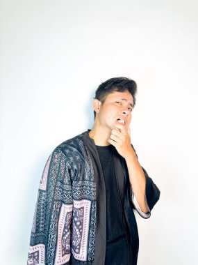 Geleneksel siyah bornoz giyen genç bir adam düşünceli görünürken işaret parmağıyla hareket ediyor. Bu ifade bir fikri veya farkındalığı akla getiriyor, beyin fırtınası, ilham ve problem çözme gibi kavramlara uygun kılıyor..