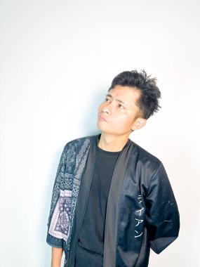 Geleneksel desenli siyah bornoz giyen genç bir adam, kafası karışık bir ifadeyle yana bakıyor. Onun hafif eğimli kafası ve çatık kaşları şüphe, merak ya da belirsizlik taşır, bu görüntü kafa karışıklığı, karar-mak temaları için uygundur