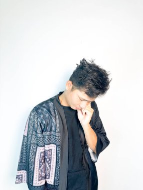 Geleneksel desenli siyah bornoz giyen genç bir adam, kafası karışık bir ifadeyle yana bakıyor. Onun hafif eğimli kafası ve çatık kaşları şüphe, merak ya da belirsizlik taşır, bu görüntü kafa karışıklığı, karar-mak temaları için uygundur