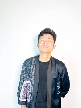 Geleneksel desenli siyah bornoz giyen genç bir adam, kafası karışık bir ifadeyle yana bakıyor. Onun hafif eğimli kafası ve çatık kaşları şüphe, merak ya da belirsizlik taşır, bu görüntü kafa karışıklığı, karar-mak temaları için uygundur