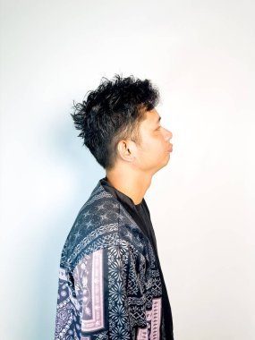 Geleneksel desenli siyah bornoz giyen genç bir adam, kafası karışık bir ifadeyle yana bakıyor. Onun hafif eğimli kafası ve çatık kaşları şüphe, merak ya da belirsizlik taşır, bu görüntü kafa karışıklığı, karar-mak temaları için uygundur