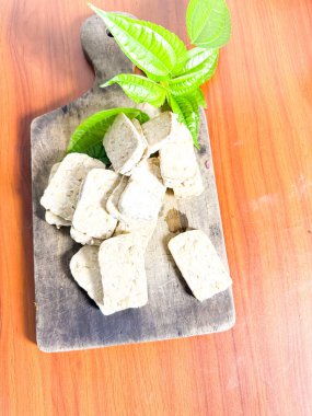 Yeşil bitkisel yapraklı, ahşap bir tahta kesme tahtasına dizilmiş taze tempo dilimlerinin yakın çekimi. Bu geleneksel mayalanmış soya fasulyesi ürünü Endonezya mutfağında ve popüler bir bitkisel protein kaynağıdır. Yemek, vejetaryen ve hea için ideal.