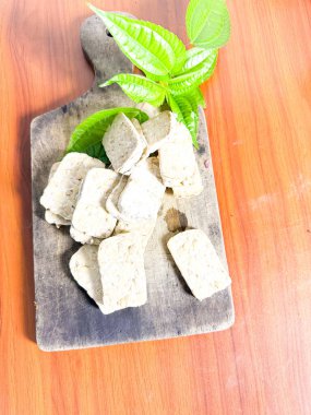 Yeşil bitkisel yapraklı, ahşap bir tahta kesme tahtasına dizilmiş taze tempo dilimlerinin yakın çekimi. Bu geleneksel mayalanmış soya fasulyesi ürünü Endonezya mutfağında ve popüler bir bitkisel protein kaynağıdır. Yemek, vejetaryen ve hea için ideal.