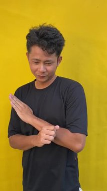 Asyalı genç adam izole edilmiş beyaz arka planda yumruğunu gösteriyor.