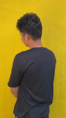 Sarı tişörtlü genç adam kameraya bakıyor, beyaz arka planda izole edilmiş..