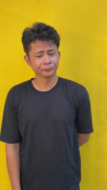 Sarı tişörtlü, kahverengi tişörtlü, sarı tişörtlü genç bir Asyalı.