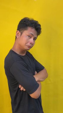 Sarı tişörtlü ve siyah arka planlı genç Asyalı adam.