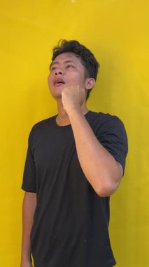 Sarı tişörtlü genç Asyalı adam, yumruklu, siyah izole edilmiş, kırpma yolu olan.