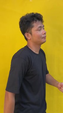 Beyaz arka planda izole edilmiş sarı tişörtlü Asyalı adam.