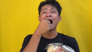 Sarı arka planda pirinç yiyen bir adam.