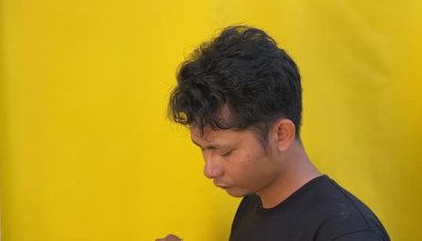 Siyah tişörtlü genç Asyalı adam ve sarı arka planlı siyah.,