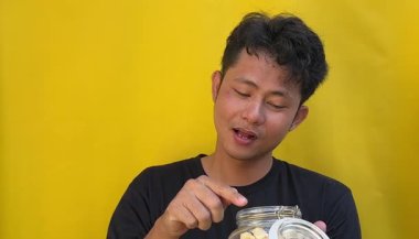 Asyalı bir adam sarı fasulye yer ve elinde içer.